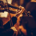 Close up shot of a woman performing on a violin during a concert.